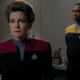 Captain Janeway sadly looks away from Tuvok, as he stands at attention in her office.